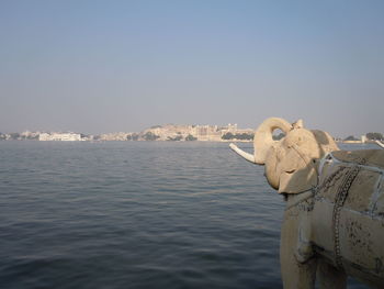 Statue by river against clear sky