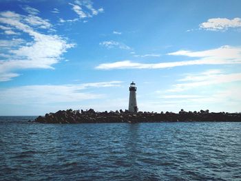 Lighthouse by sea against sky