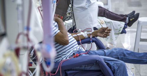 Midsection of patient sitting by medical equipment in hospital