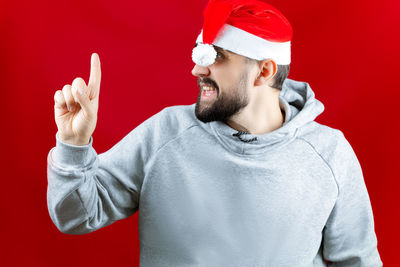 Portrait of mid adult man wearing hat against red background