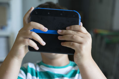 Close-up of boy holding video game in front of his face