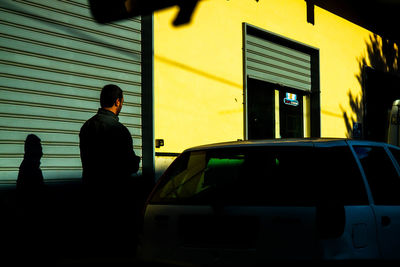 Man standing by yellow car in city