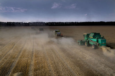 Combine harvesters on wheat field against sky