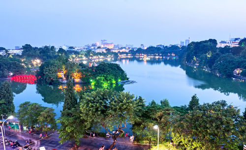 High angle view of illuminated buildings by river against sky