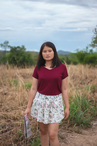 Portrait of a beautiful young woman standing on field