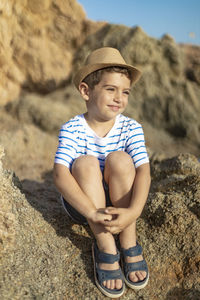 Portrait of smiling boy sitting on rock