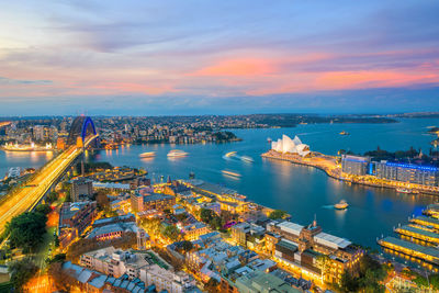 High angle view of illuminated city by river against sky