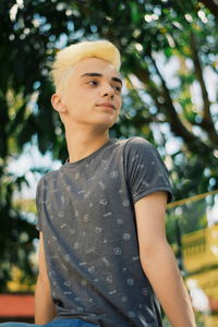 Low angle view of smiling teenage boy looking away