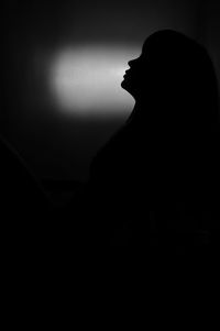 Silhouette of man and woman standing against dark background