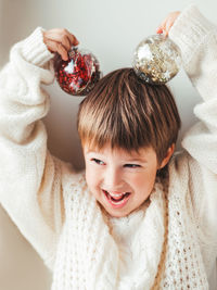 Kid with decorative balls for christmas tree.boy in cable-knit oversized sweater. new year, christma