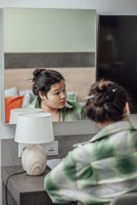 Asian girl expression in mirror suggests silent conversation with herself,  thoughts, feelings