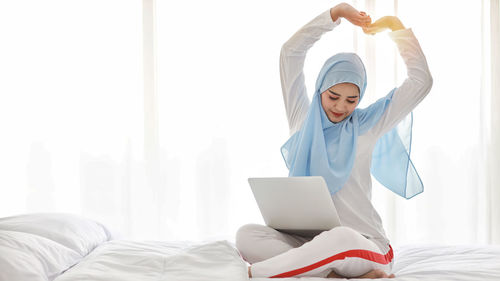 Woman using mobile phone while sitting on bed