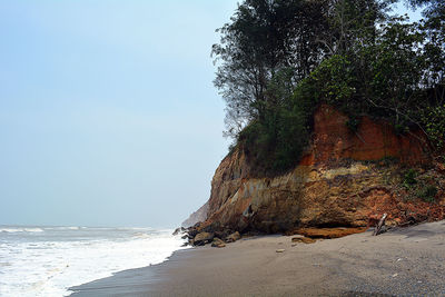 Rock on beach against clear sky