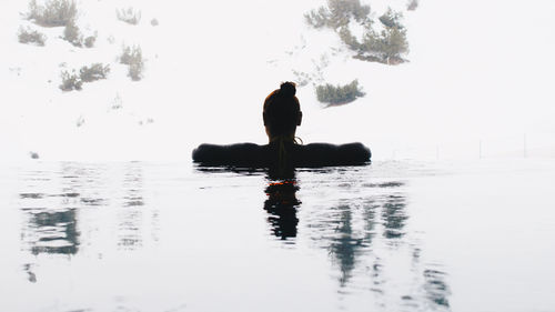 Man sitting in lake against sky
