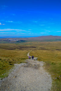 People on arid landscape against blue sky