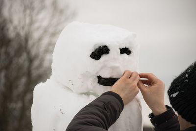 Close-up of man making snowman