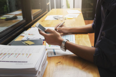 Midsection of businessman using mobile phone in office