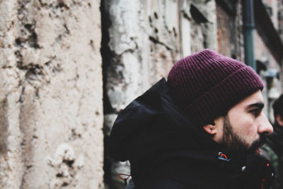 Portrait of young man wearing hat against wall