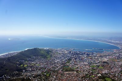 Aerial view of city by sea against clear blue sky