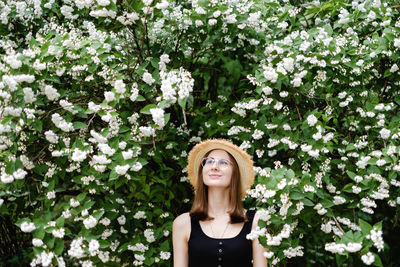 Portrait of a beautiful woman standing by flower plants