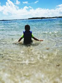 Rear view of man in sea against sky