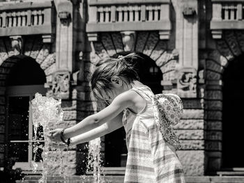 Girl standing by fountain by building