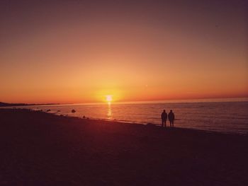 Silhouette of people on beach at sunset