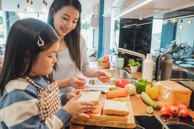 Mother and daughter on cutting board at kitchen