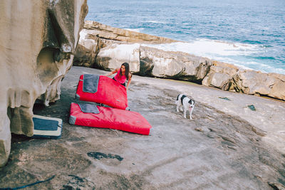 Woman adjusting mattress by rock formation at beach