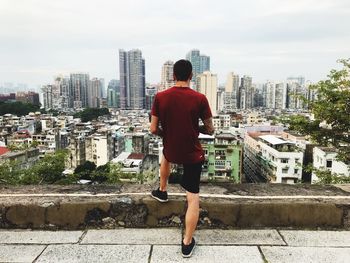 Rear view of man standing by buildings against sky