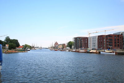 River by buildings against clear blue sky