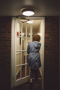 Full length rear view of woman walking by door