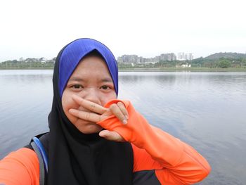 Close-up portrait of young woman against river