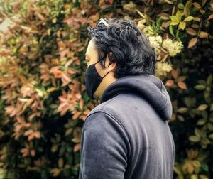 Rear view of man standing against flowering plants.