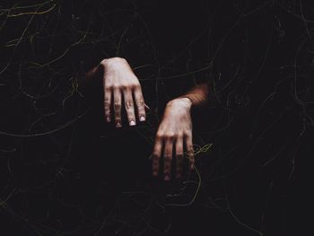 Cropped image of hand coming out from ivy covered wall at night