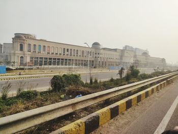 Road by buildings against clear sky