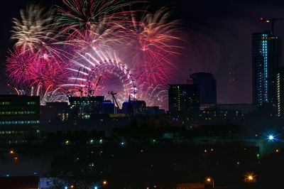 Firework display over illuminated buildings in city at night