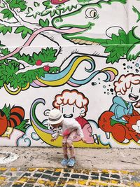 Full length of woman standing against graffiti wall