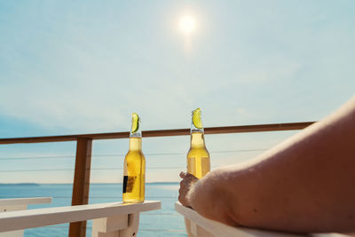 Cropped hand of man holding beer bottle while relaxing at tourist resort during sunny day