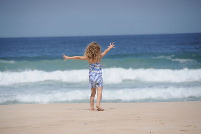 Rear view of girl standing on shore at beach