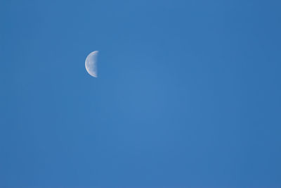 Low angle view of moon against blue sky