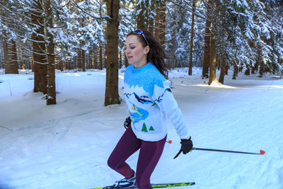 Mid adult woman skiing on snow in forest