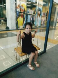 Portrait of smiling girl sitting on swing