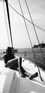 Woman sitting on boat at sea against sky