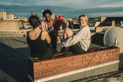 Portrait of smiling female friends after yoga on rooftop during sunrise