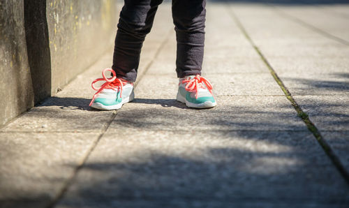 Low section of woman standing on footpath