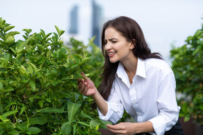 Young woman smiling while sitting on plant