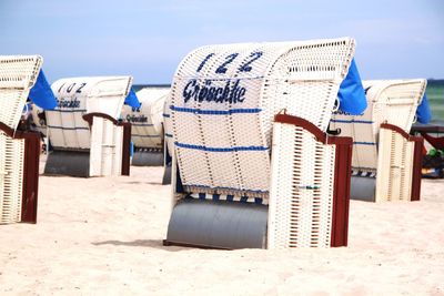 Hooded chairs on beach against sky