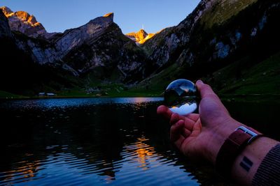 Man hand on lake against mountain range