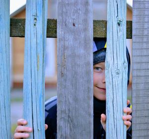 Portrait of girl hiding behind fence